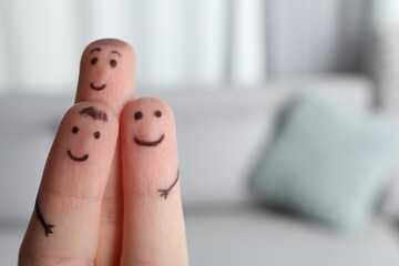 Naklejka premium Three fingers with drawings of happy faces on blurred background, space for text