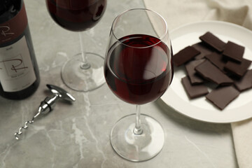 Glass of red wine with chocolate on light marble table