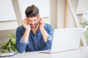 Businessman suffering from strong pain in his head while sitting at office desk