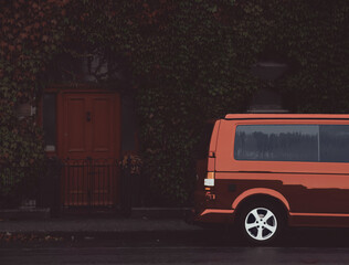 Obraz premium Red minivan parks in front of a house with a red door, ilustration