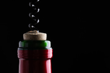 Opening wine bottle with corkscrew on dark background, closeup. Space for text