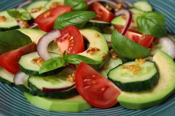 Tasty salad with cucumbers on blue plate, closeup