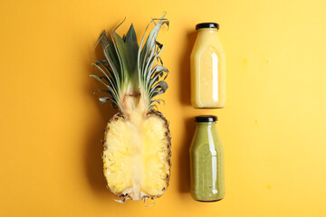 Bottles with delicious colorful juices and cut pineapple on yellow background, flat lay