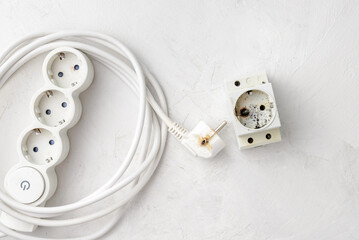 Broken extension cord and socket as a result of a short circuit in the electrical network. - obrazy, fototapety, plakaty
