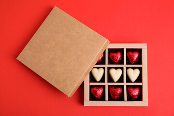 Tasty heart shaped chocolate candies on red background, flat lay. Happy Valentine's day