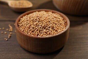 Mustard seeds in wooden bowl on table, closeup