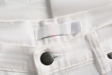 Blank clothing label on white jeans, top view