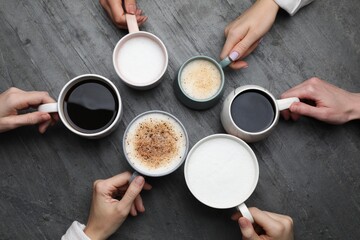 People holding different cups with aromatic hot coffee at grey table, top view