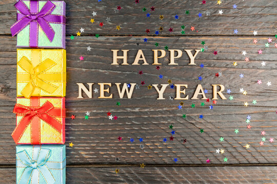 Happy New Year Festive Background. Gift Boxes And Wooden Text. Multicolored Stars Confeti