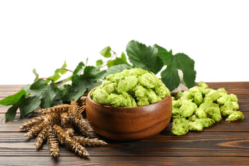 Fresh hop flowers and wheat ears on wooden table against white background