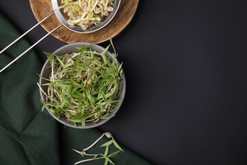 Mung bean sprouts with bowl and strainer on black table, flat lay. Space for text
