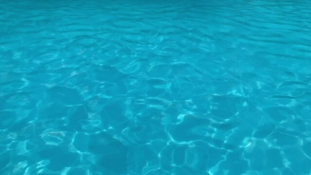 Pure blue water in the pool with light reflections. abstract background
