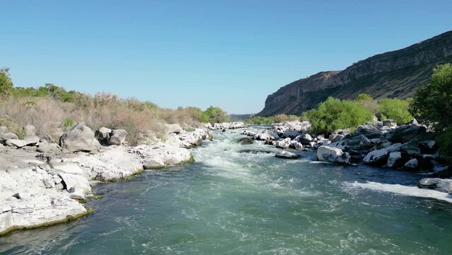 Aerial footage of a river rushing through white sun bleached rocks. Location, Snake River, Twin Falls Idaho.