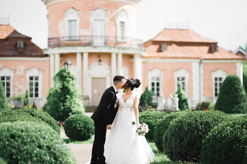 Beautiful bride and groom embracing and kissing on their wedding day outdoors