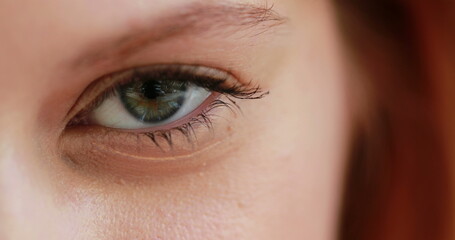 Obraz premium Macro closeup of girl opening eye, redhair woman with green eyes