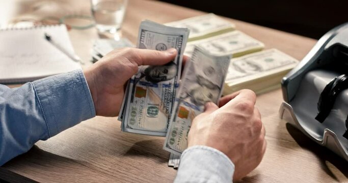 Close up of person hands holding and counting many dollars at desk at workplace. Paper money calculation. Financial operations. Bank worker hands count dollars cash. Dollar banknotes being counted