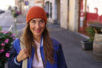 Caucasian woman wearing a beanie and holding a backpack outdoors  