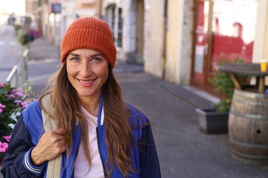 Caucasian woman wearing a beanie and holding a backpack outdoors  