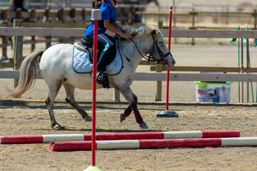 Little girl that rides a white pony during Pony Game competition at the Equestrian School