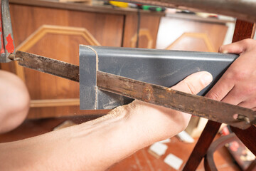 Trimming a wooden plinth with a manual jigsaw.