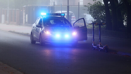 Akcja policji we mgle wieczorem w mieście. - Sygnalizator błyskowy niebieski na dachu radiowozu...