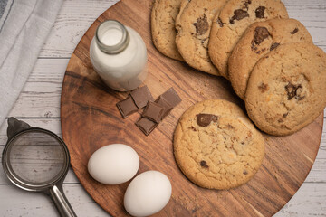 Chocolate chip cookies on wooden background with ingredients