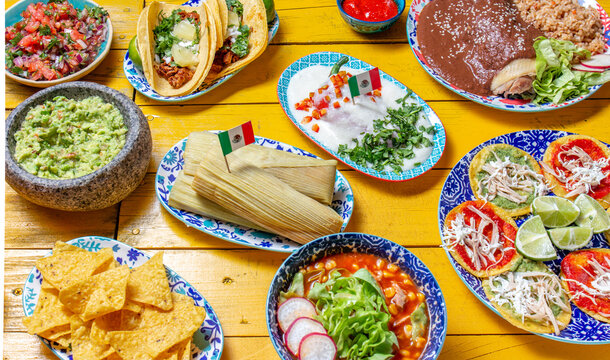Mexican festive food for independence day independencia - chiles en nogada, tacos al pastor, chalupas pozole, tamales, chicken with mole poblano sauce. Yellow background.