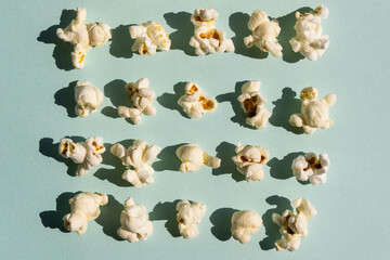 Rowes of salt popcorn on the light blue background. Concept of cinema or watching TV.