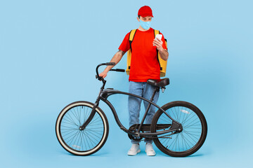 Courier Wearing Mask Using Cellphone Standing With Bike, Blue Background