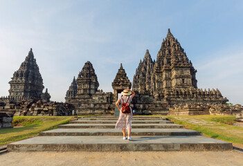 Tourist looking at a landmark at the Prambanan temple. Asian woman with white dress and wearing hat.