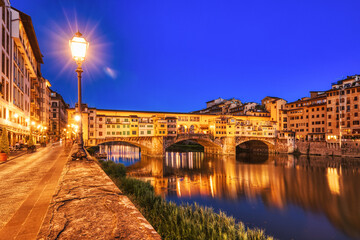 Obraz premium Illuminated Ponte Vecchio Bridge with Reflection in Arno River at Dusk, Florence