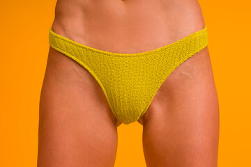 yellow swimming trunks on a beautiful woman. close-up on a yellow background.