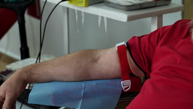 Close-up of a man's hand tied with a tourniquet. Preparing a patient for blood donation at a donor center.