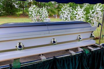 A funeral service is held in a cemetery followed by the coffin being lowered into grave by an...