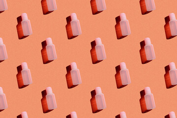 cosmetic bottle of pink color on an orange background with a hard light