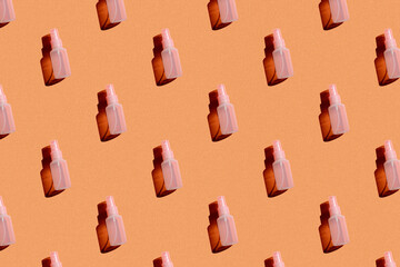 cosmetic spray bottle pink on orange background with hard light