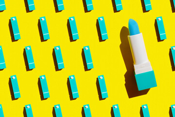 hygienic lipstick in the form of a milk carton of blue color on a yellow background with a hard light