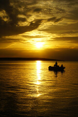 Obraz premium Family on a boat on a summer vacation in a beautiful sunset at sea