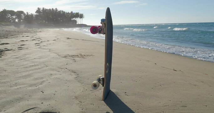 Skateboard in sand on tropical beach.