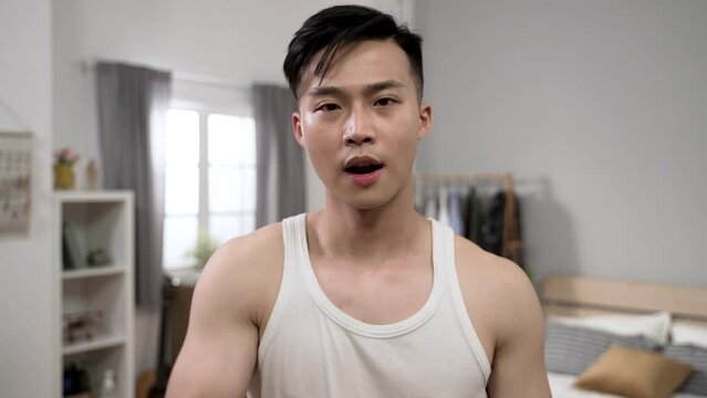 slow motion with shoulder shot confident asian man facing camera like mirror while cheering himself up with clenched fist and deep breath in the morning at home
