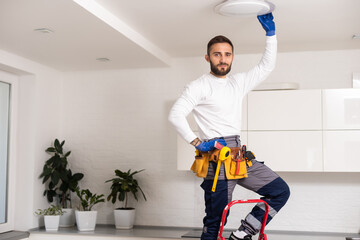 Electrician worker man assembling electric lamps in new apartment.