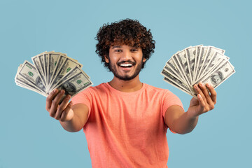 Happy indian man holding cash in both hands and smiling