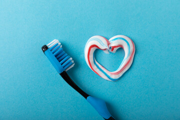 Oral care. Dental care. Composition with a toothbrush and a heart with toothpaste on a blue...
