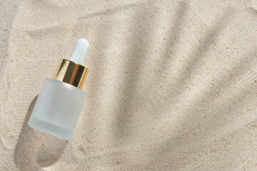 Fototapeta na wymiar face serum of glass bottle with a pipette on a natural background with sand. Essential oil for moisturizing body skin. mockup of beauty fashion cosmetic bottle dropper product with skincare concept.