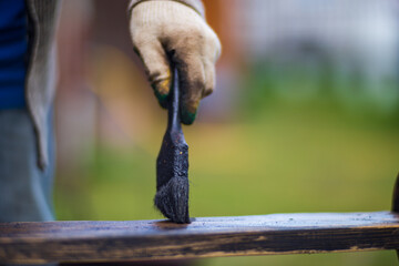 A man applies paint to a wooden surface with a brush. Lacquer work