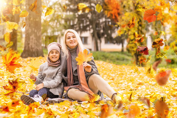 happy family: mother and child little daughter play cuddling on autumn walk in nature outdoors