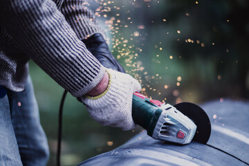 Man working with grinder saw, close up view on tool. Electric saw and hands of worker with sparks. Worker cutting metal with grinder