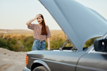 Woman sad and angry about car breakdown on road trip alone and putting her hands on her head from not understanding, car problem