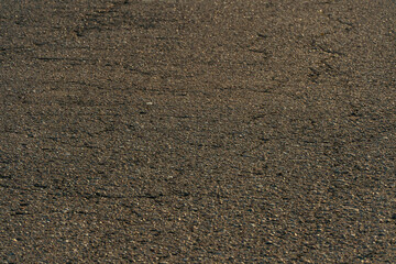 old asphalt with holes and irregularities close-up. Unsafe and emergency road section. Empty grey asphalt background.