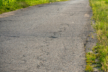 old asphalt with holes and irregularities close-up. Unsafe and emergency road section. Empty grey asphalt background.